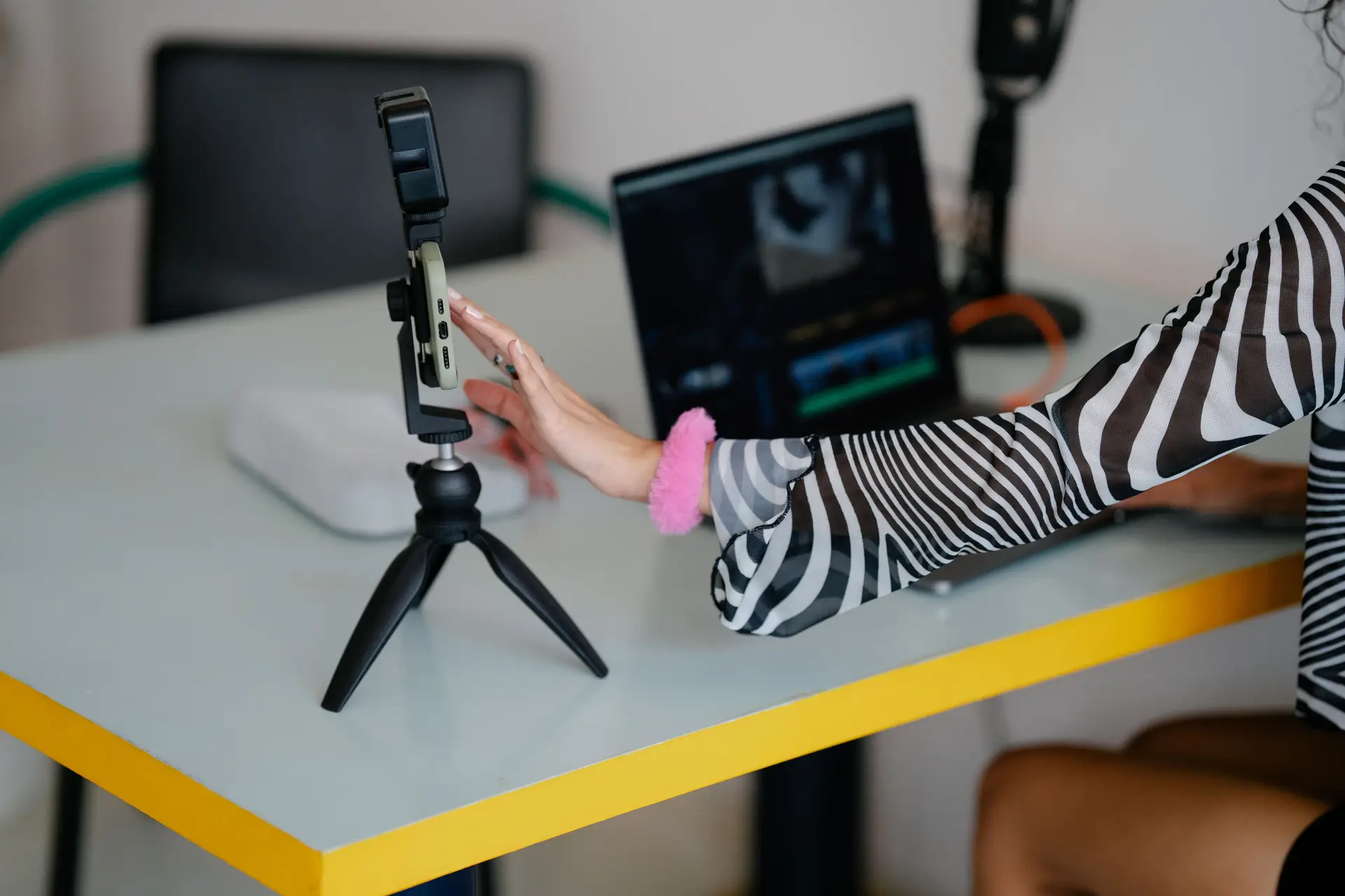 Frau justiert Smartphone auf Stativ für Videoaufnahme